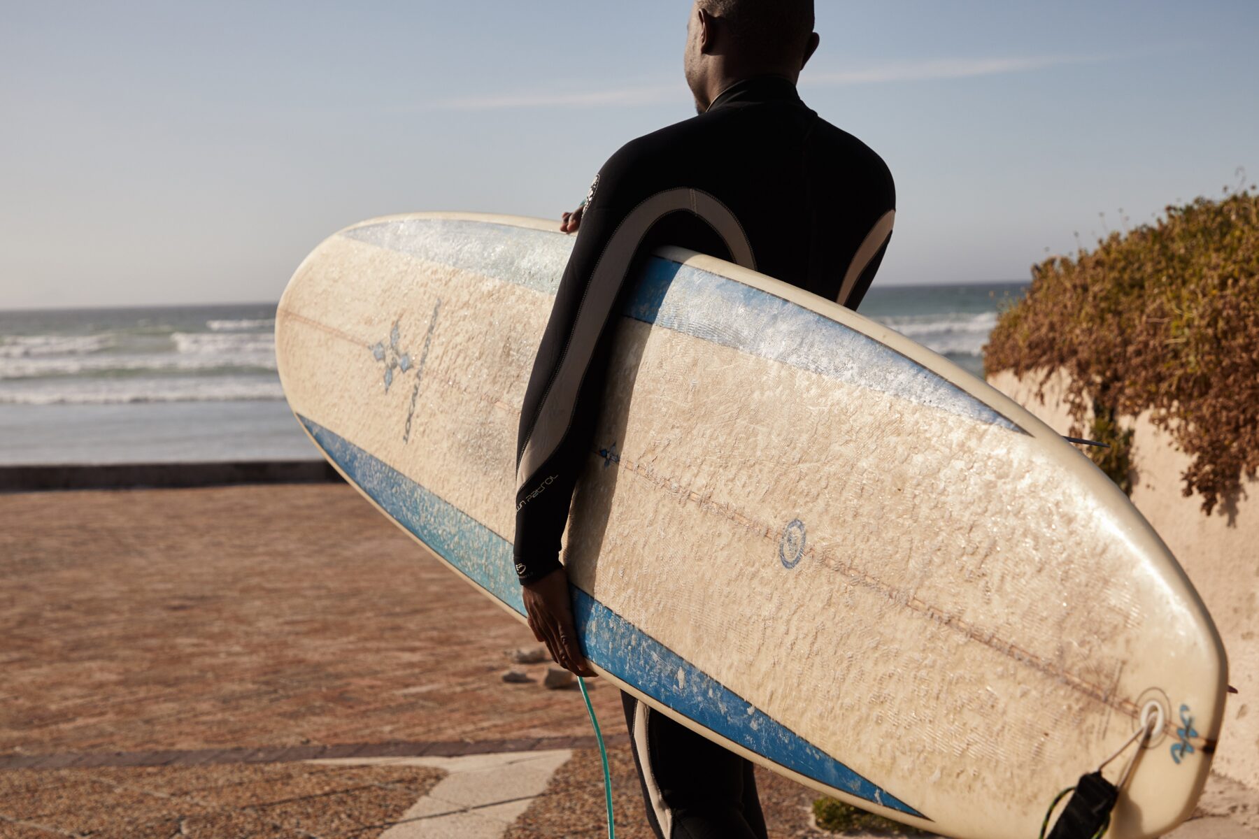 man in wetsuit met surfboard