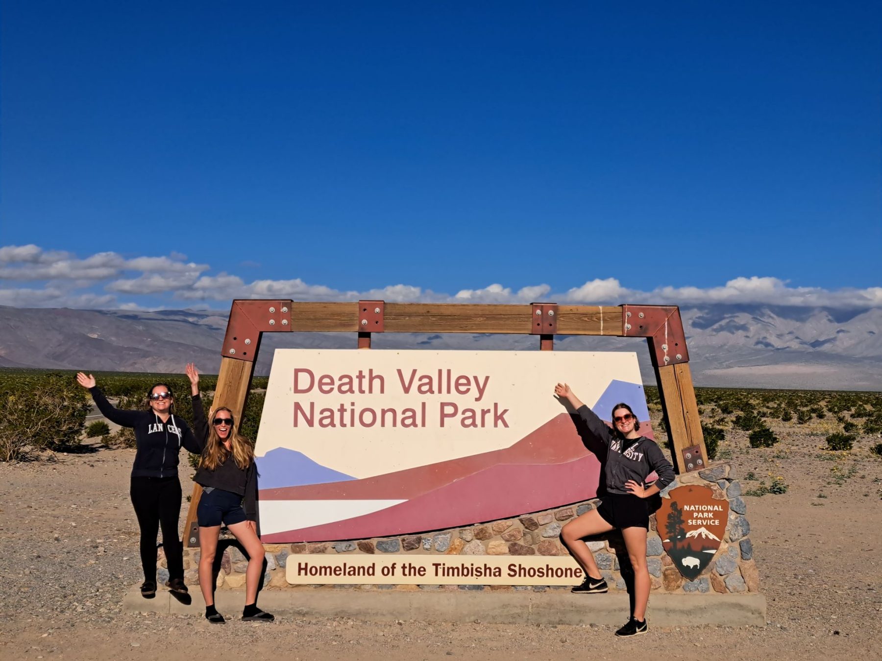 drie vrouwen bij het welkomsbord van Death Valley