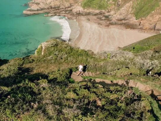 Een man rent over coastal cliffs op Guernsey.