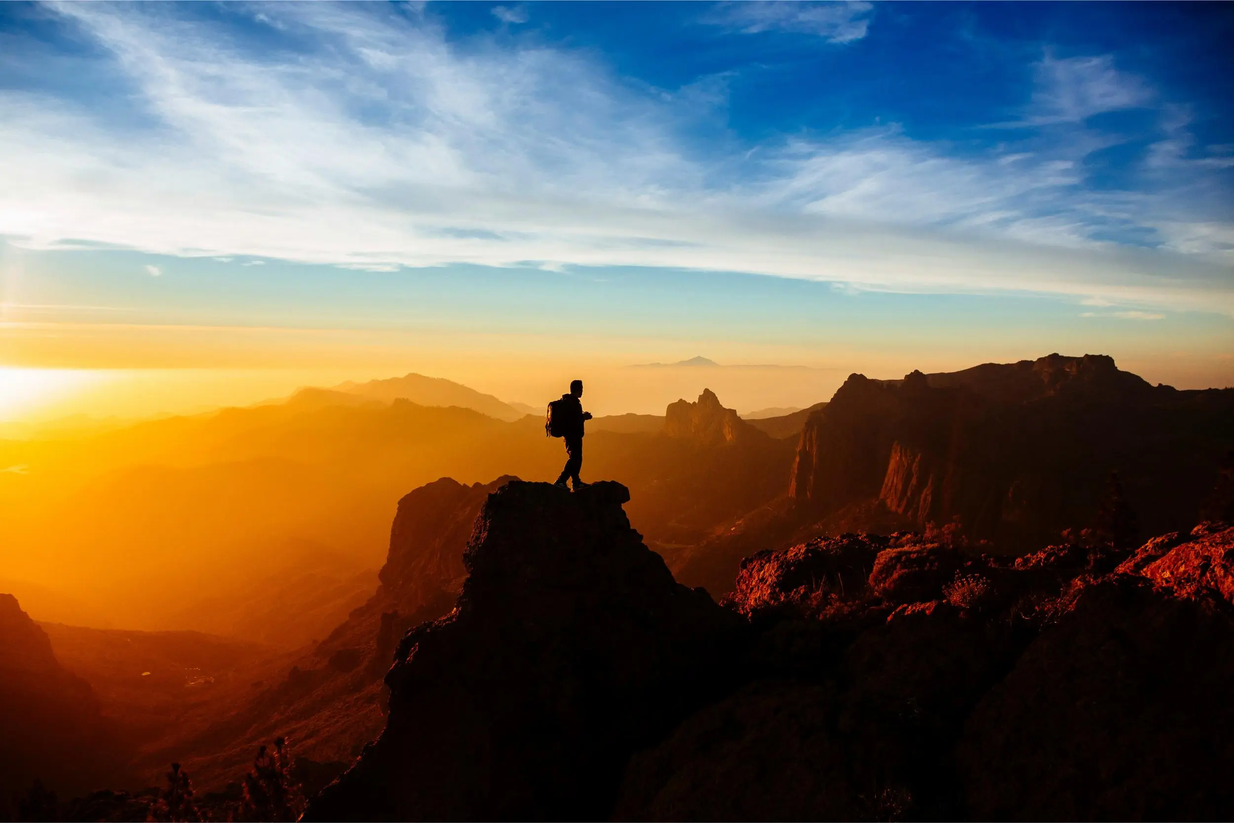 Een persoon op een gebergte tijdens een hike op Gran Canaria met de zonsondergang op de achtergrond.